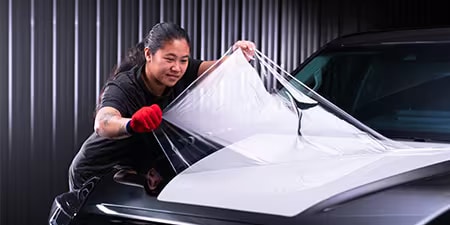 Wrap installer applying film to the hood of a vehicle.
